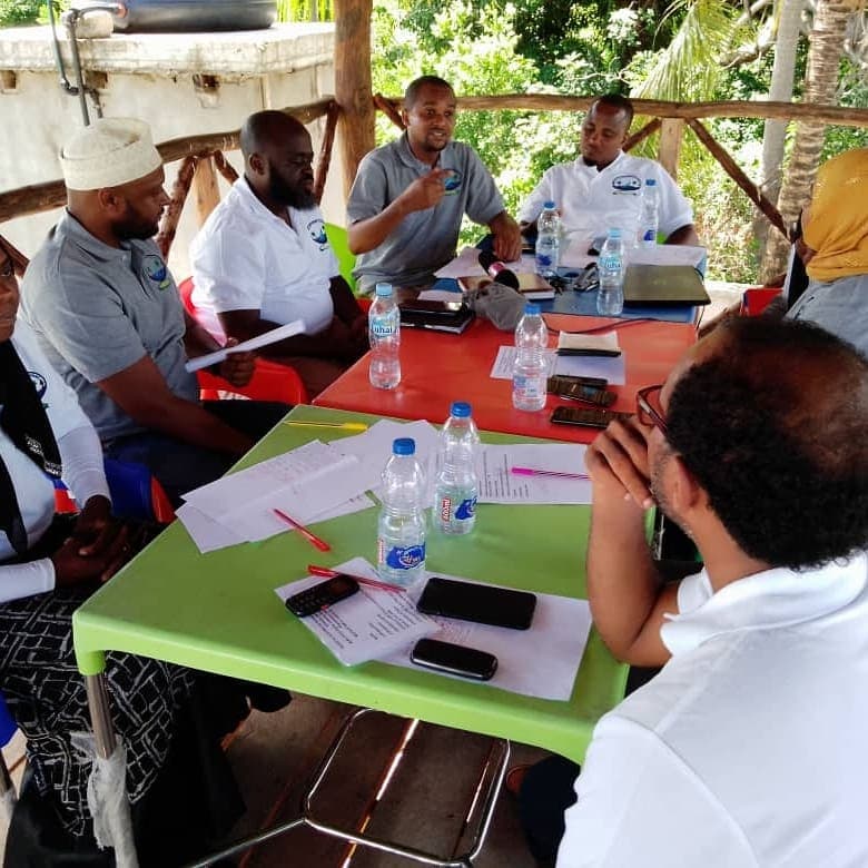 Members in a planning meeting under an open-air shelter