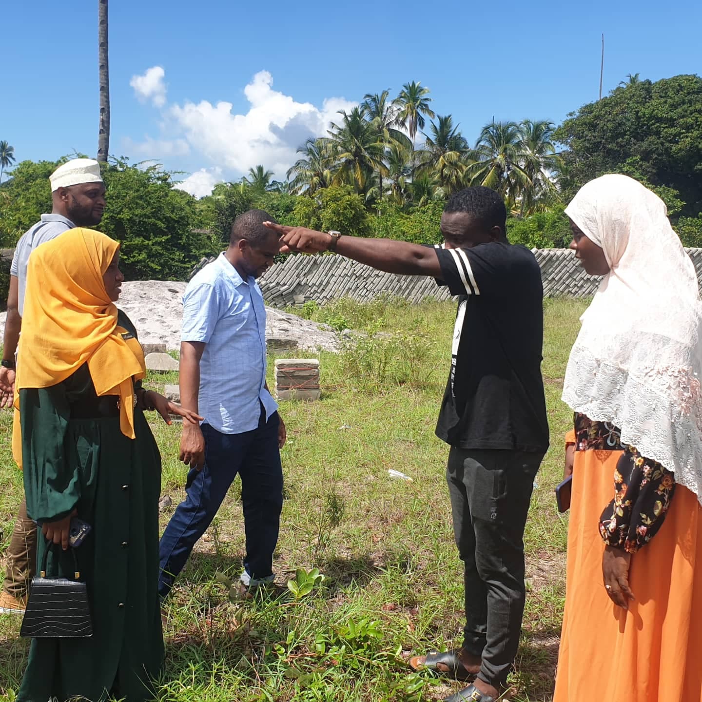 Members surveying the office plot with boundary string lines and foundation markers
